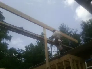 Carpenter setting a ridge beam over a new addition frame — Ice Dam Removal by Roofing Brothers in Roaring River