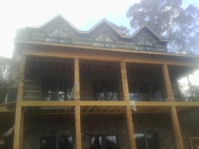 Dormers and porch framing on a large log home under construction — Roof Coating work by our crew in Roaring River